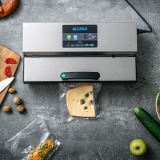 Produktfoto eines Allpax Vakuumierers auf einem Küchentisch, umgeben von frischem Gemüse, Käse und Küchenutensilien, Beispiel für hochwertige Produktfotografie im Bereich Haushaltsgeräte.